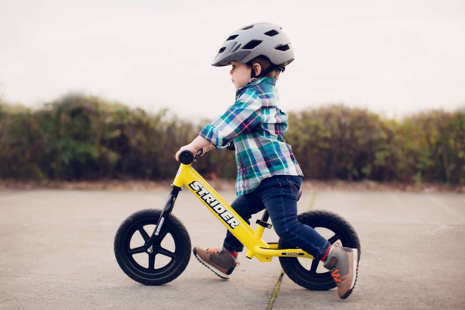 A boy rides a yellow Strider balance bike