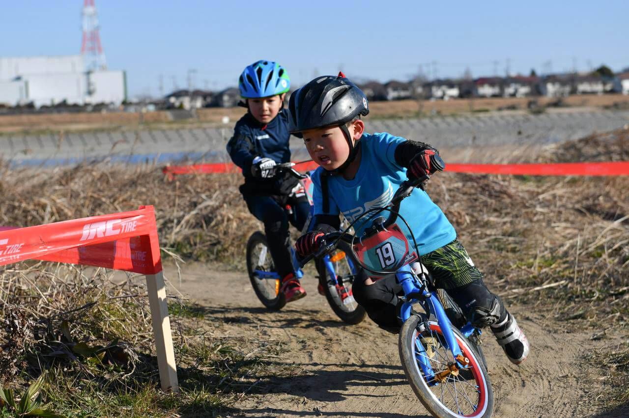 Two young racers make a turn on a dirt race course